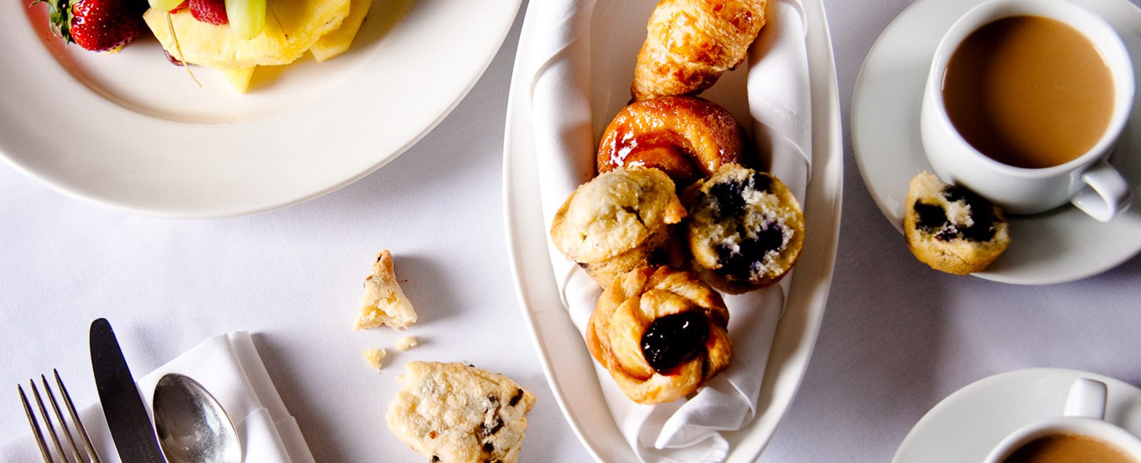 Photograph of some of breakfast menu options to include; muffins, pastries, coffee, and fresh fruit.