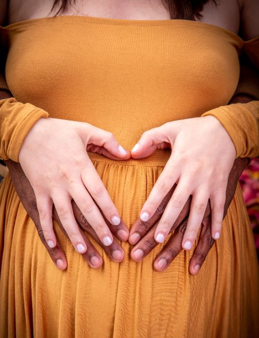 picture of mother to be and father to be's hand on the mothers belly