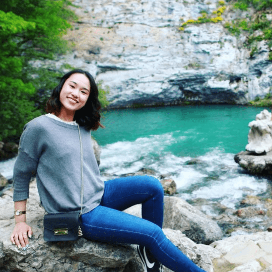 Photo of our sales & reservations assistant sitting on a rock posing for the picture