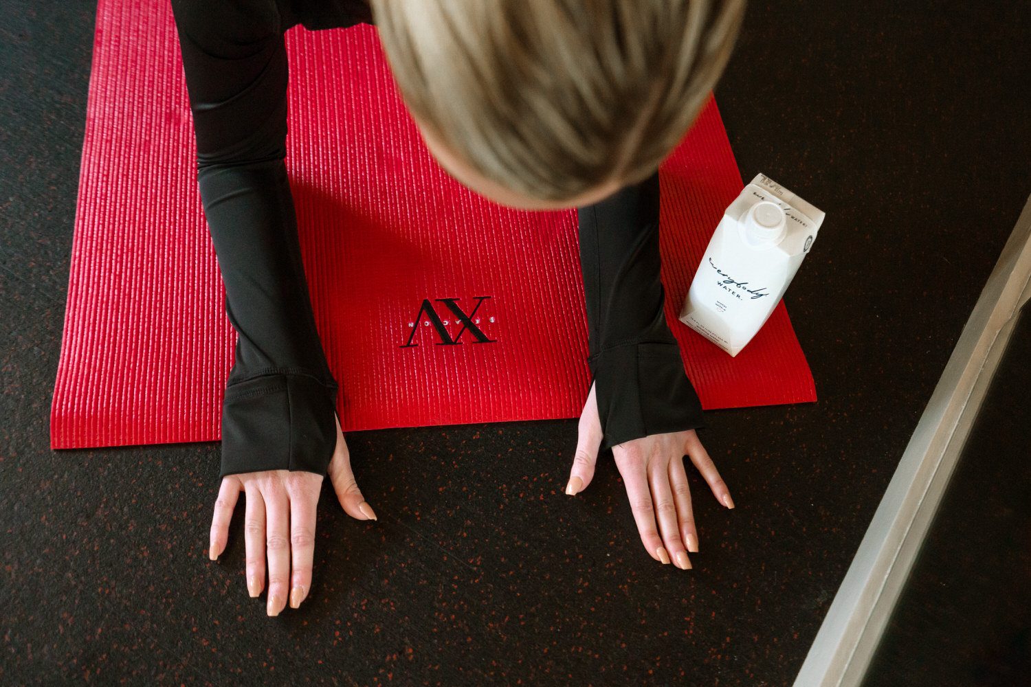 Young lady on the XV Beacon Yoga mat in a hand pose next to our everybody water