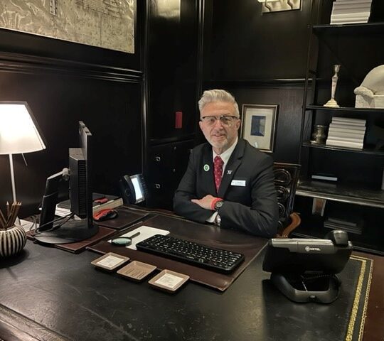 XV Beacon's concierge team member sitting at the concierge desk smiling in the hotel lobby
